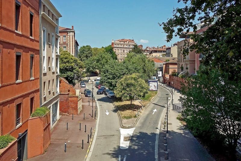 Avenue de la Garonnette : avenue vue d'en haut, chaussée courbe, arbres verts et immeubles de brique sous un ciel bleu