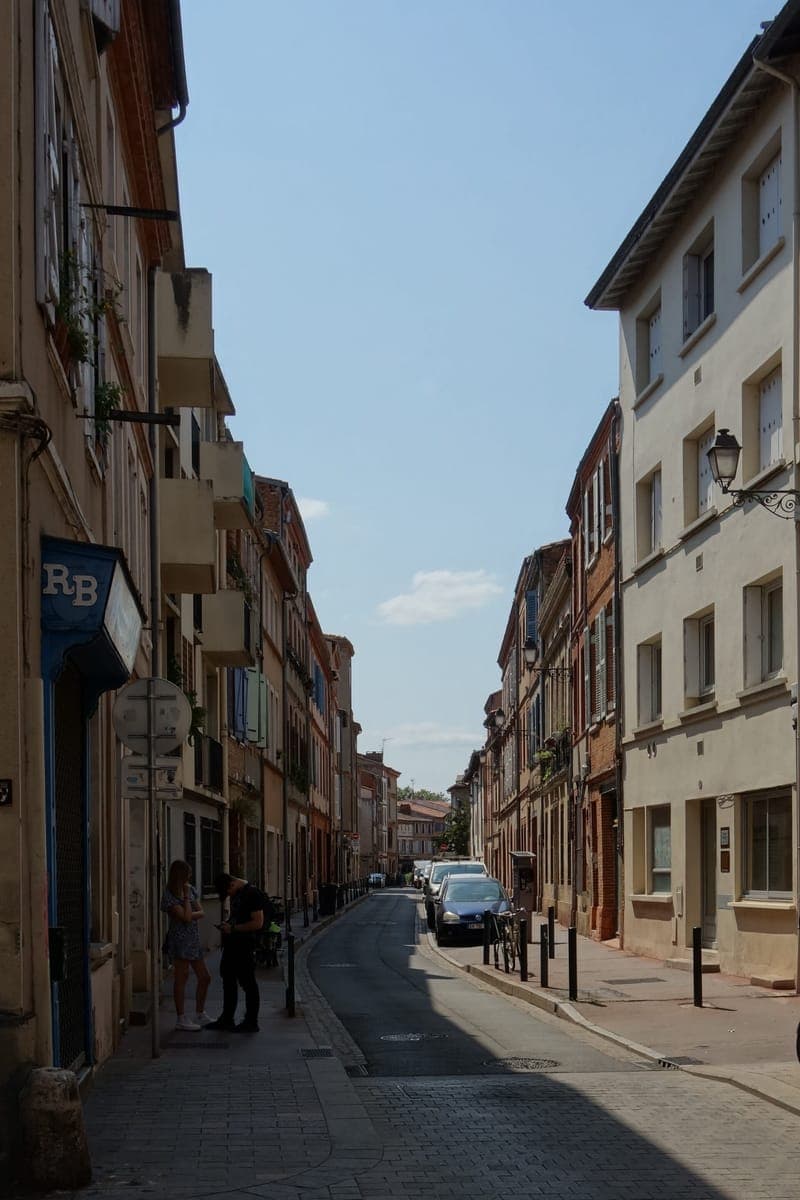 Grande-rue Saint-Nicolas : rue étroite et pavée, façades de brique et d’enduit, quelques voitures garées au fond
