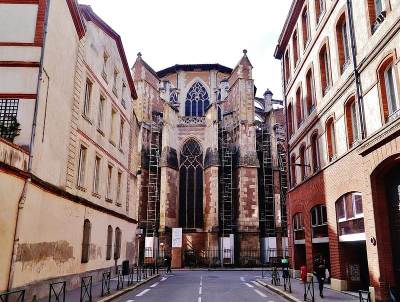 Rue pavée menant au chevet de la cathédrale, échafaudages, façades de brique de part et d’autre