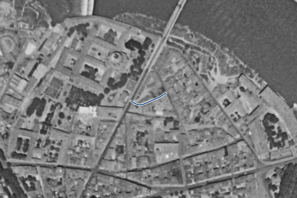 Vue aérienne de la rue Arnaud Baric en 1954, en noir et blanc, la voie tracée en bleu