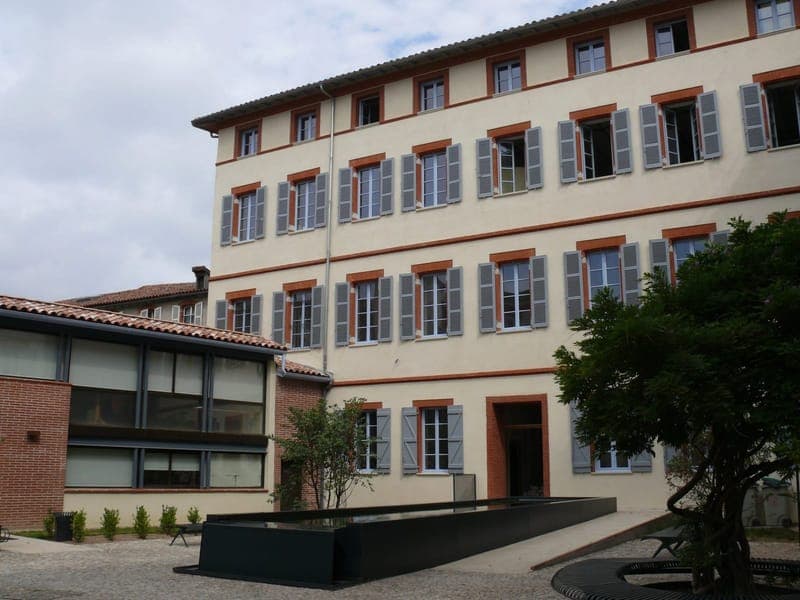 Rue de la Fonderie : rue étroite bordée de façades de brique, église à rosace et portail gothique, scooter sur le trottoir