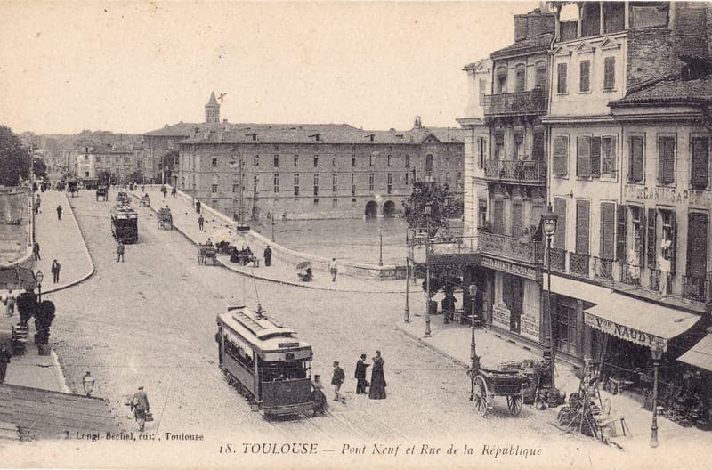 Carte postale ancienne d'une place avec tramway, calèches et passants, grand bâtiment au fond