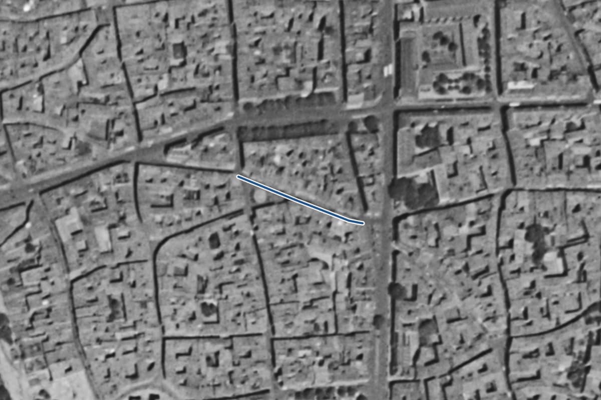 Vue aérienne de la rue de la Trinité en 1954, en noir et blanc, la voie tracée en bleu