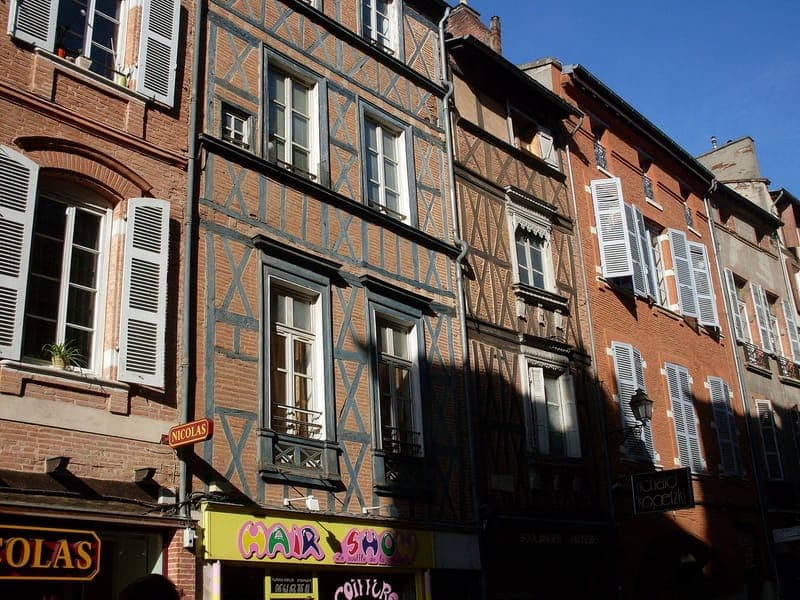 Rue des Filatiers : façades en colombage et en brique le long de la rue, sous un ciel bleu