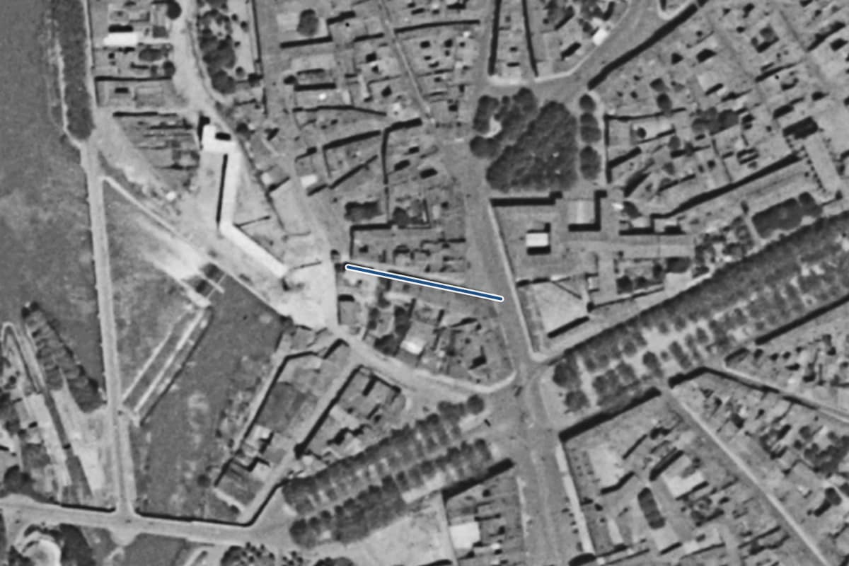 Vue aérienne de la rue des Renforts en 1954, en noir et blanc, la voie tracée en bleu