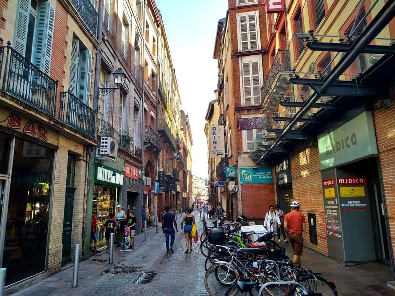 Rue des Tourneurs : rue étroite et pavée bordée de façades de brique, vélos garés à droite, passants au loin