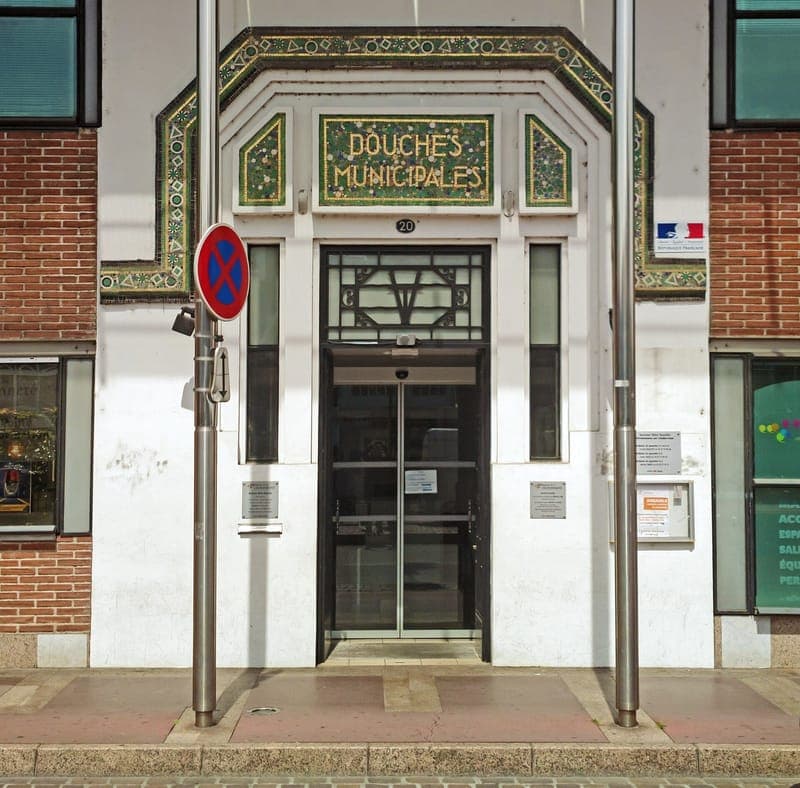 Entrée Art déco de mosaïque verte et dorée portant l’inscription « Douches municipales »