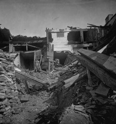 Photographie ancienne : ruines d’habitations, poutres et débris de bois, murs fissurés